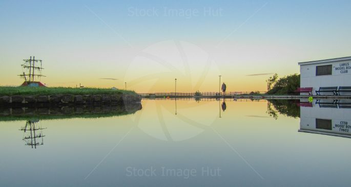 Walking your dog on a very peaceful, calm morning alongside a little boating pond. This was taken at a small seaside town on the West coast of Scotland