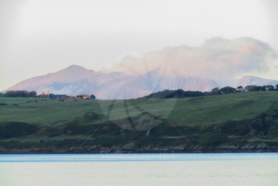 Low clouds on distant mountains being lit by the sun as she starts to rise on a beautiful calm morning
