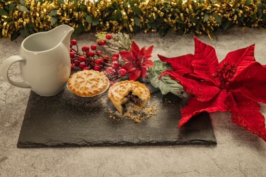 Christmas food with mince pies sitting on slate with Christmas decorations in background