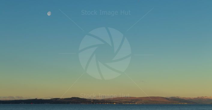 Stunning moon as sun begins to rise over the sea