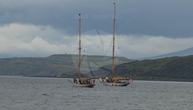 Two large racing yachts lowering their sails ready to come into harbour