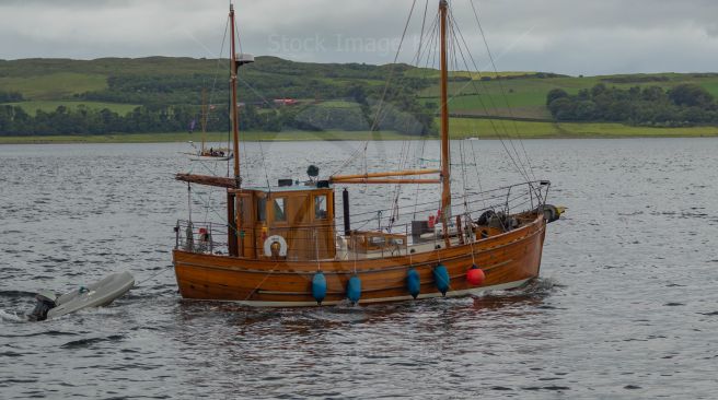Classic looking boat towing a Rib and heading out to sea