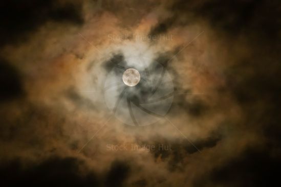A new moon appearing behind clouds on night sky