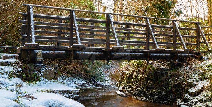 Old wooden bridge with river flowing below on a cold winter morning
