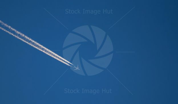 An airplane leaving white trails across a bright blue sky