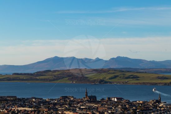 Picturesque seaside town with ferry crossing to Millport and distant mountains of Arran in background,  West Coast of Scotland