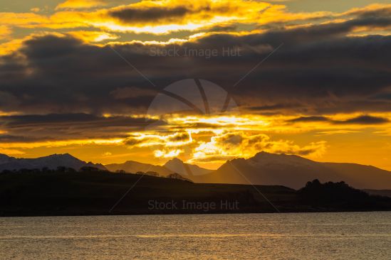 Sun lighting up sky as she sets behind hills
